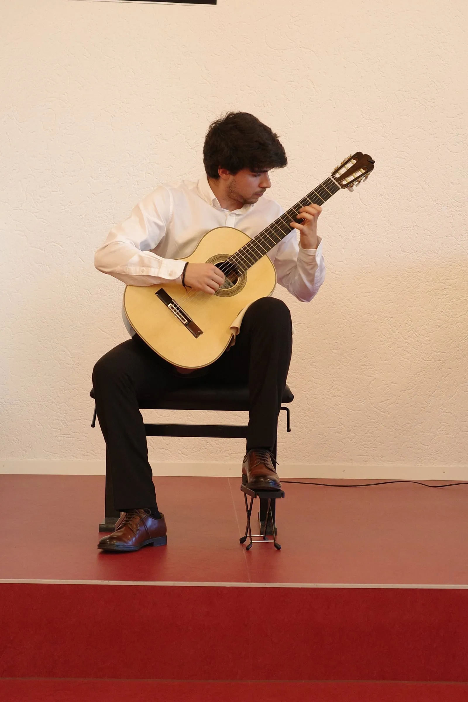 Miguel Ferreira in recital, in a white shirt, absorbed in the guitar.