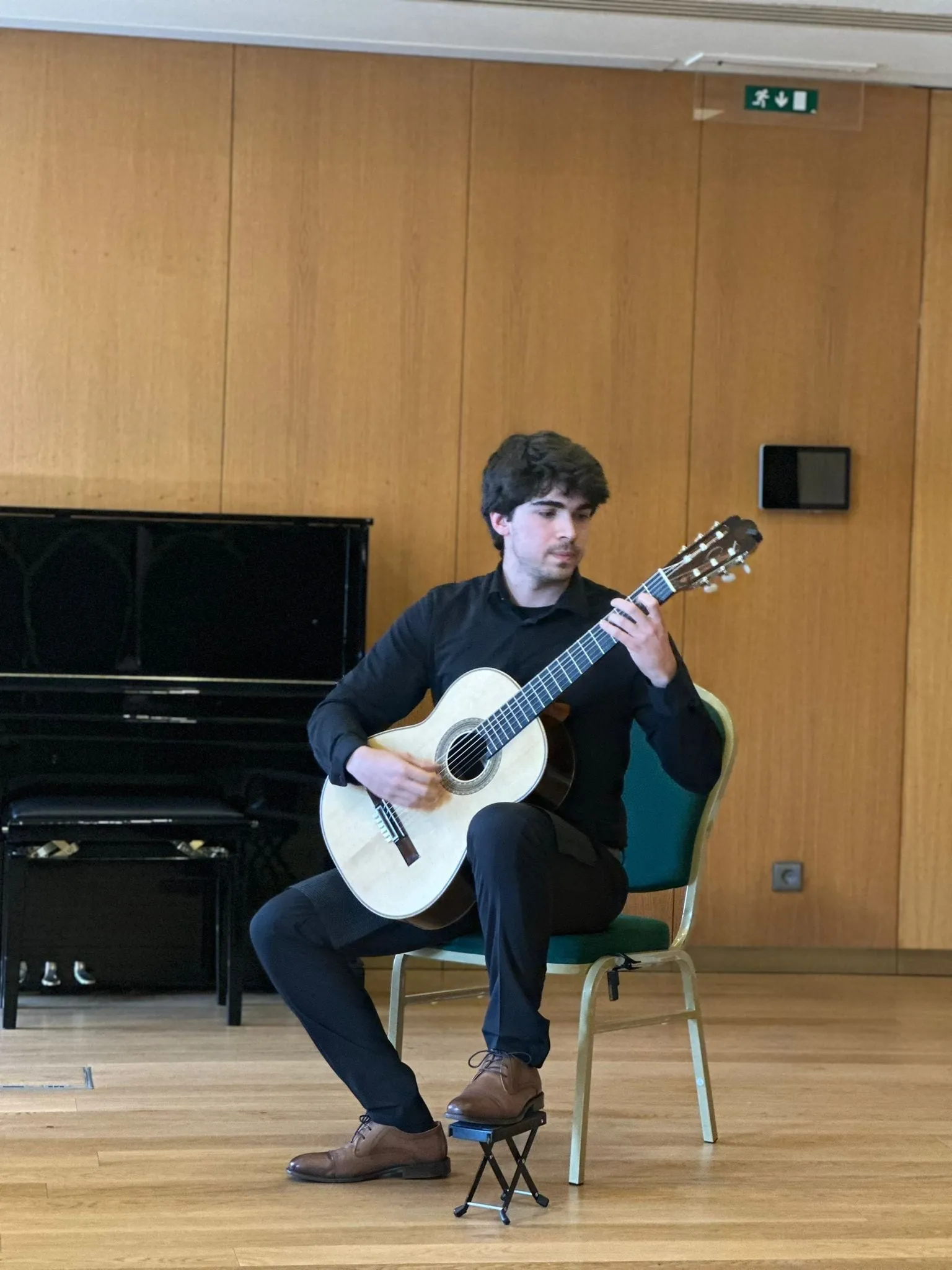 Miguel Ferreira playing, in a dark jumper, in a wood-panelled room.