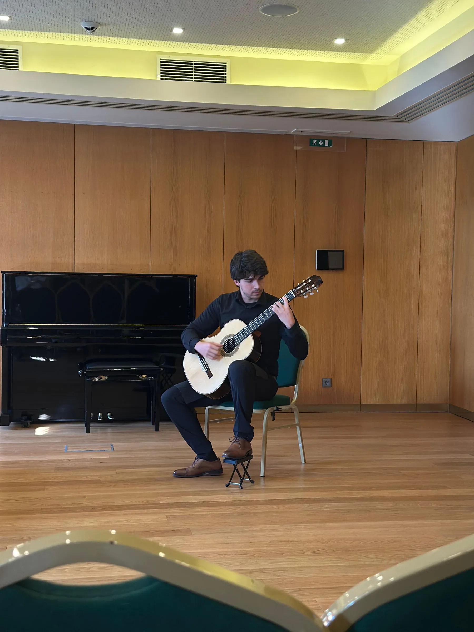 Miguel Ferreira playing in a wood-panelled hall, a piano behind him.